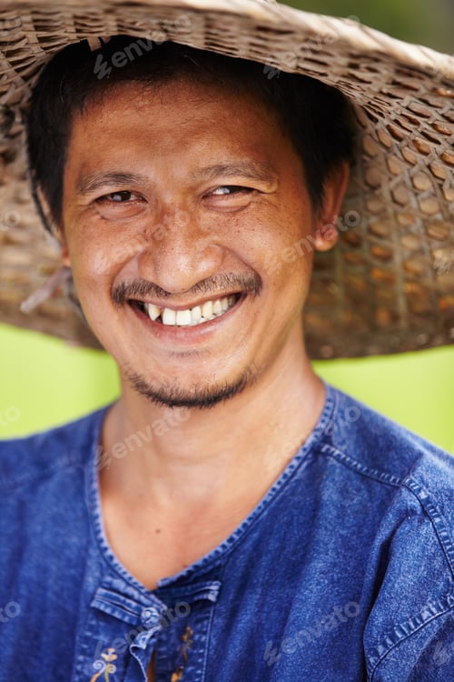 Preview: Closeup portrait of a Thai rice paddy worker wearing a traditional hat