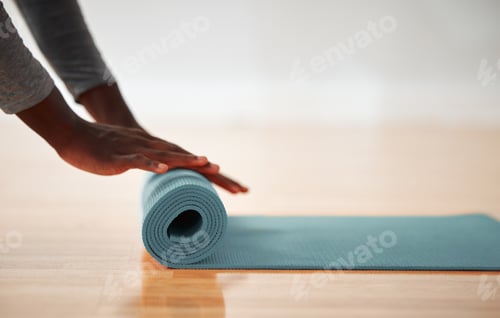 Preview: Person Rolling Out Yoga Mat on Wooden Floor