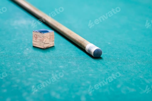 Preview: A cue stick and a chalk on a pool table