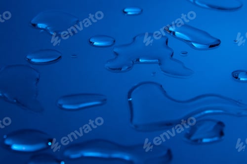 Preview: Drops of cosmetic substance on a blue background. Background image for a cosmetics store.