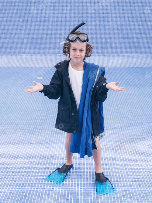 Preview: Boy in diving equipment and coat between empty pool