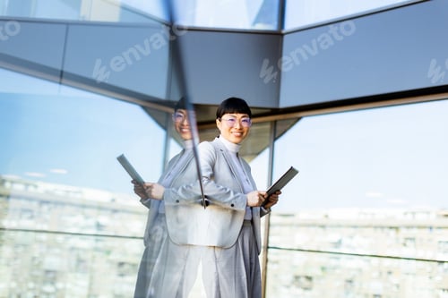 Preview: Successful entrepreneur smiles while holding tablet in modern office with city view