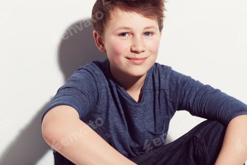 Preview: Filled with potential. Young adolescent boy sitting against a white background with a smile.