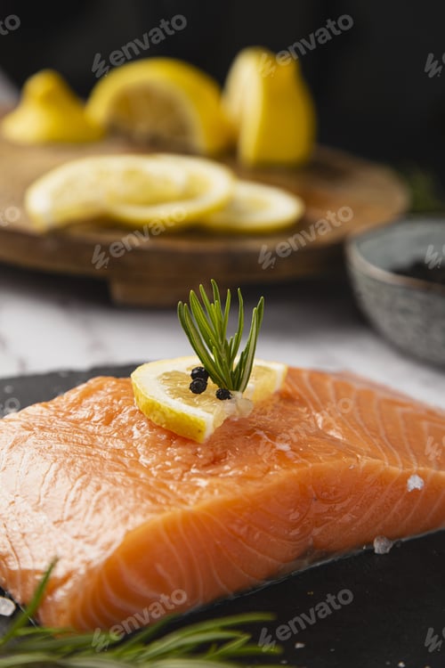 Preview: Vertical shot of raw salmon fillet with a lemon slice and rosemary on the table