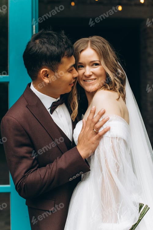 Preview: Beautiful European bride and her Asian groom posing against the backdrop of cafes and large windows.