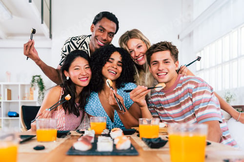 Preview: Multiethnic group of young friends meeting at home and eating sushi