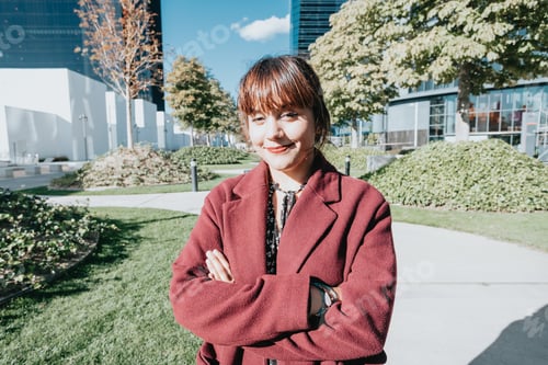 Preview: Smiling young businesswoman standing outside office smiling to camera during a rest