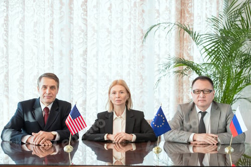 Preview: Row of business partners or delegates from EU, USA and Russia sitting by table
