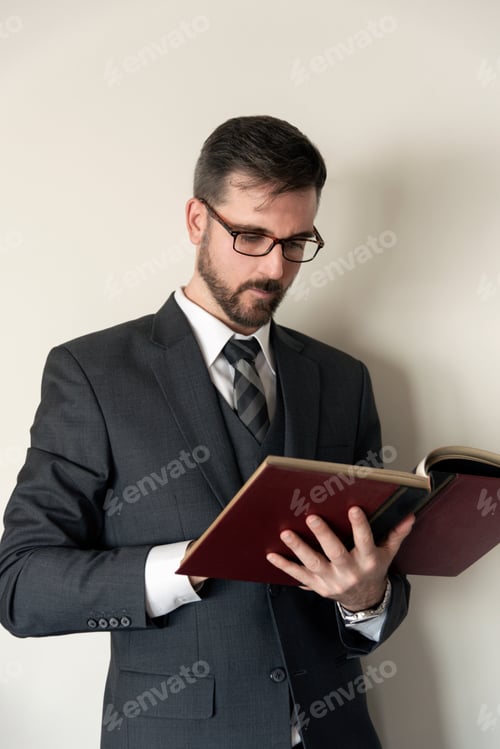 Preview: Man in suit reading a from a large hardcover book