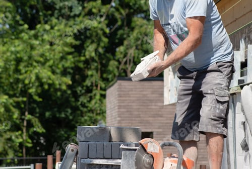 Preview: masonry worker the bricklayer makes the facade of the house from gray bricks