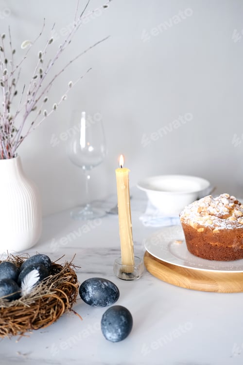 Preview: Easter table setting with candles, willow branches and blue eggs in nest for family brunch or dinner