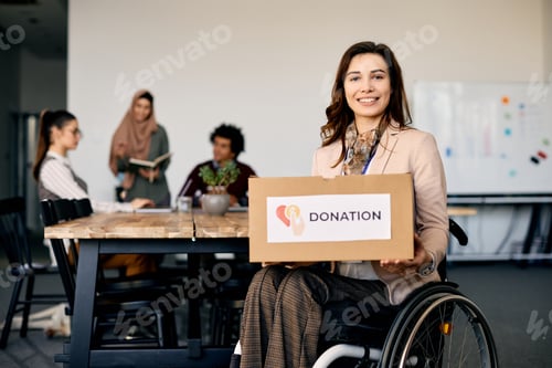 Preview: Happy businesswoman in wheelchair holding donation box and looking at camera.