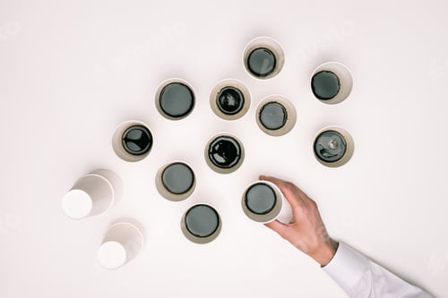 Preview: top view of person taking one of many disposable coffee cups isolated on white