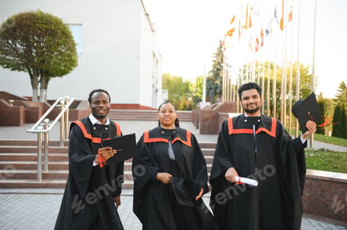 Preview: Group of multiracial graduate students with diplomas on university background