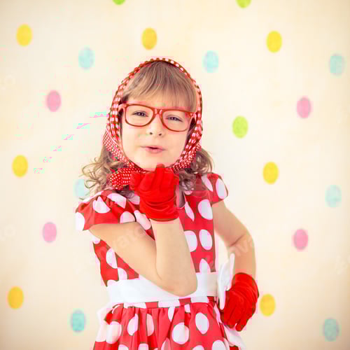 Preview: Playful Child in Red Polka Dot Dress Blowing Kiss