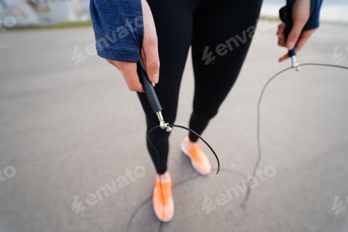 Preview: Young woman exercise with skipping rope outdoors