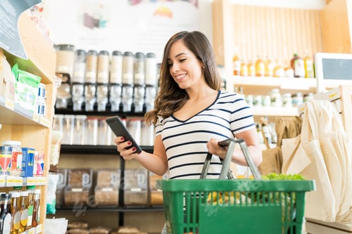 Preview: Customer Using Phone While Shopping In Supermarket