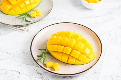 Preview: Ripe sliced mangoes on plates on the table. Tropical fruit