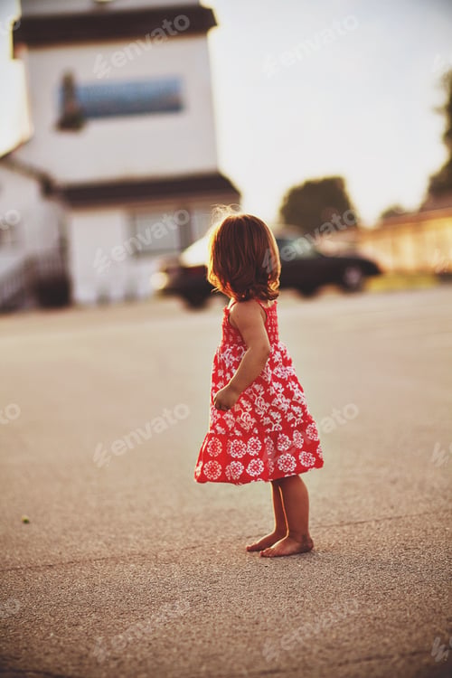 Small Child Standing on Street at Sunset