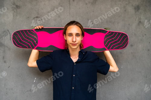 Preview: Caucasian teenage boy holding longboard looking at camera. Copy space.