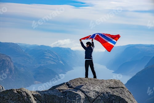 Preview: Woman with a waving flag of Norway on the background of nature