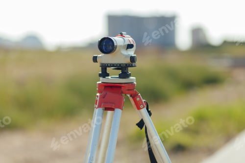 Preview: Optical level is mounted on a tripod, with a construction site in the background