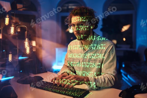 Preview: Guy in green beams works on computer in dark office room