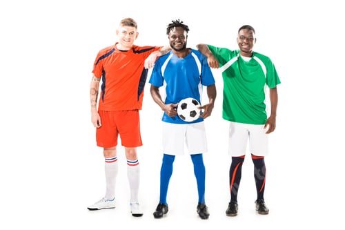 Preview: full length view of happy multiethnic soccer players standing together and smiling at camera