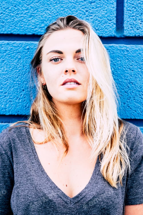 Preview: beautiful girl looking at the camera with a blue background - blonde teenager with blue eyes