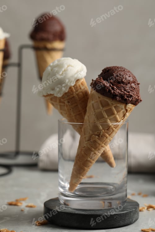 Preview: Tasty ice cream scoops in waffle cones on grey marble table, closeup