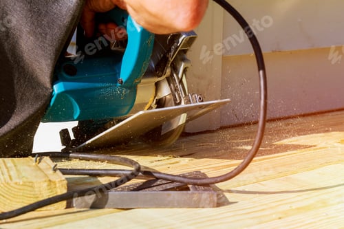 Preview: Carpenter cutting electric circular saw building wooden deck