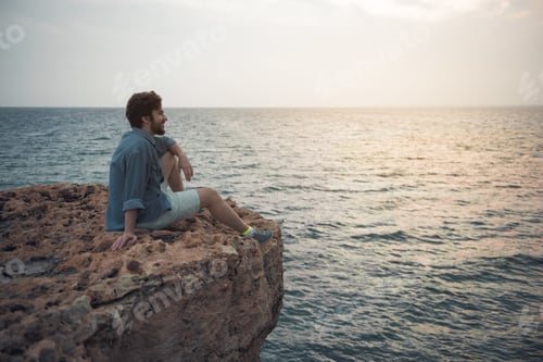 Preview: Full Length Side View Profile Of Cheerful Young Bearded Man Is Spending Time Outdoors While Sitting