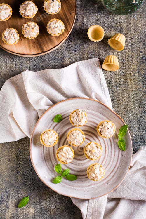 Preview: Mini tartlets with a salad of eggs, canned fish and mayonnaise on a plate. Top and vertical view