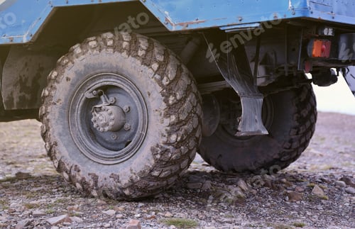 Preview: Wheel closeup in a countryside landscape with a mud road. Off-road 4x4 suv automobile with