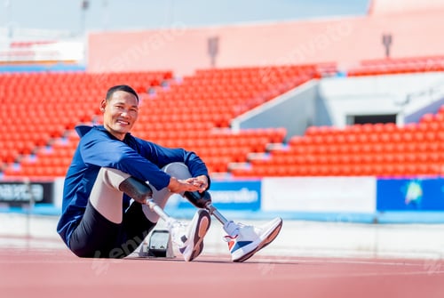 Preview: Sport man athlete prosthesis legs sit on the track and look at camera with smiling after exercise