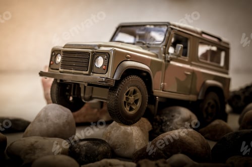 Preview: Closeup of a small toy car on rocks covered in military camouflage patters