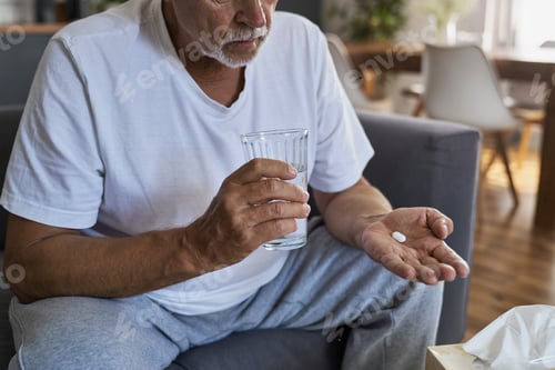 Preview: Senior caucasian man taking pill and holding glass of water