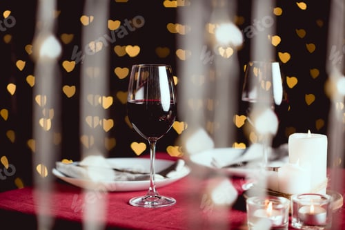 Preview: selective focus of red wine glasses with heart shaped bokeh on background