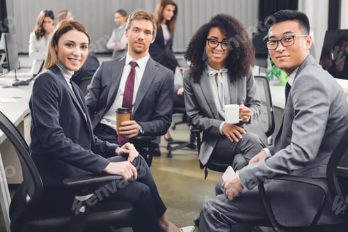 Preview: professional young multiracial business team sitting together and smiling at camera in office
