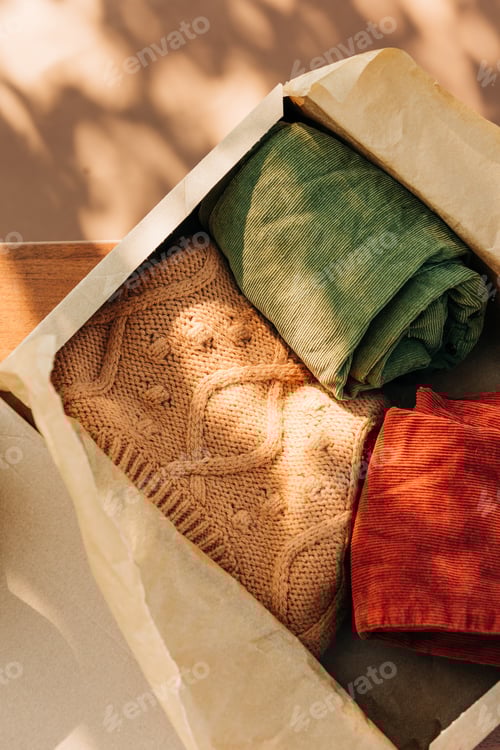 Preview: vintage sweater and pants in a cardboard box on the table.