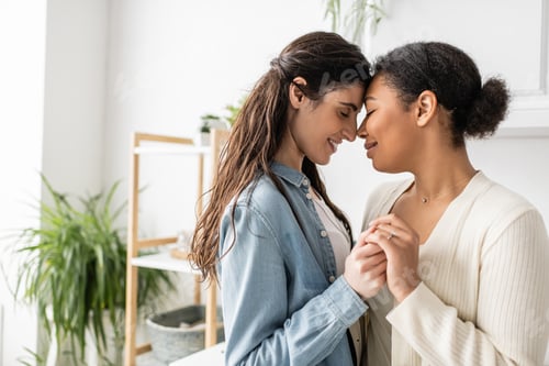 Preview: overjoyed and interracial lgbt couple holding hands during engagement