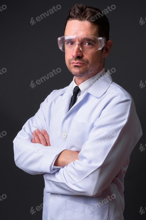 Preview: Handsome man doctor wearing protective glasses against gray background