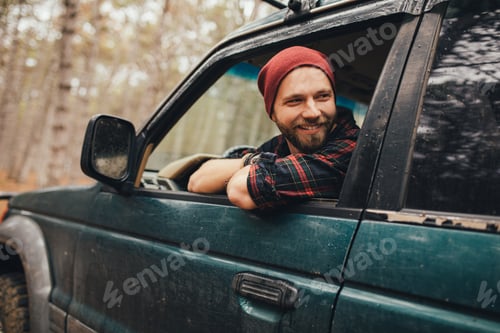 Preview: Millennial man travelling off-road by car in a forest. Wanderlust concept.