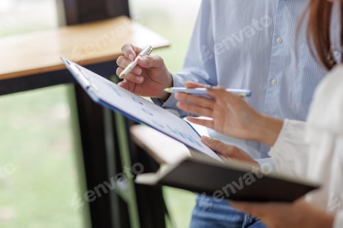 Preview: Business people discussing charts on clipboard