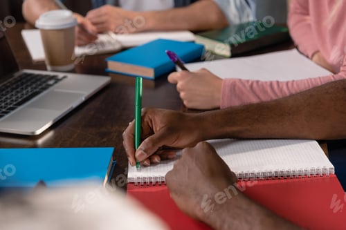 Preview: cropped view of students studying and writing in copybooks together at home