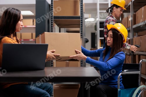 Preview: Warehouse manager giving parcel to shipment operator in wheelchair