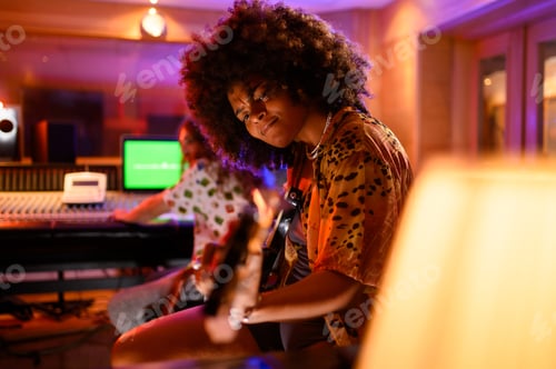Preview: Portrait of a hispanic woman playing guitar in a music studio