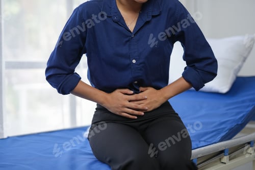 Preview: Person experiencing abdominal pain while sitting on a medical examination table.