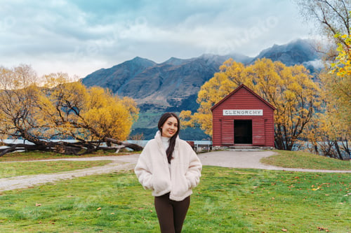 Preview: Asian woman traveling in Glenorchy with red boatshed by Lake Wakatipu on autumn at New Zealand