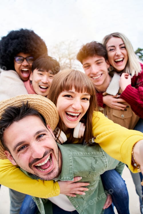 Preview: Vertical photo of friend smiling selfie in piggyback having fun together outdoors.
